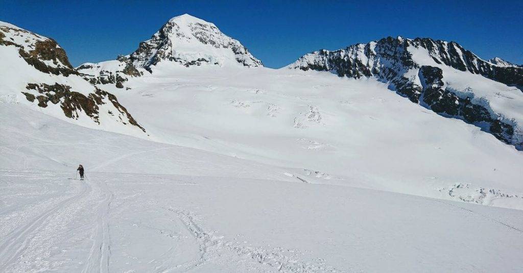 Skitourengeherin in weisser Landschaft vor dem Jungfraujoch