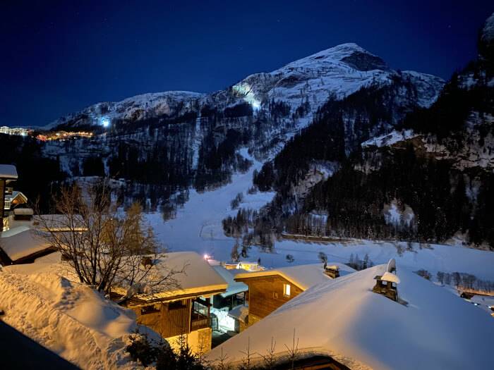 Chalets von Tignes im Winteridyll mit beleuchteten Skipisten im Hintergrund